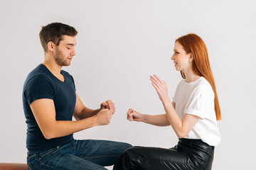 Studio shot of happy young man and woman playing rock scissors paper game on white isolated background. Concept of resolving conflicts in a peaceful and ecological way.