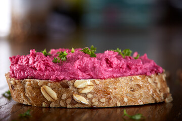 Spread made from red beet and cheese cream on a slice of bread with herbs