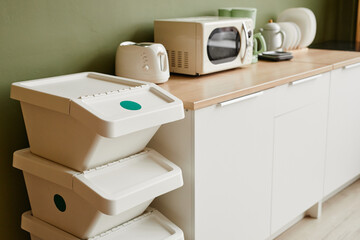 Minimal background image of kitchen interior with focus on waste sorting containers in foreground,...
