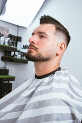 Professional barber styling hair of his client
