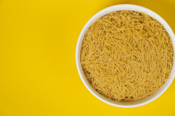 pasta for soup in a plate on yellow background