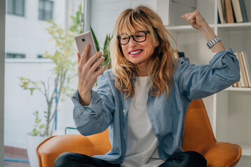 woman at home euphoric of success with mobile phone or smartphone