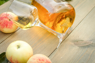 A glass of apple wine,cider, juice . Ripe summer apples are lying nearby