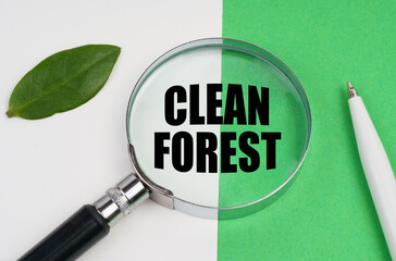 On a white-green background, a pen, a piece of paper and a magnifying glass with the inscription - Clean forest