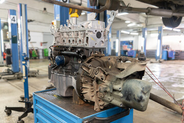 the engine removed from the car with the gearbox is on the table in the car service. Close-up, selective focus