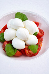 Tasty caprese salad with cherry tomatoes, white mozzarella cheese and green basil leaves