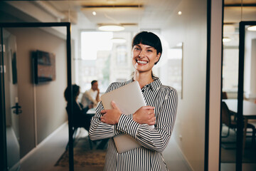 Businesswoman with a laptop laughing in an office