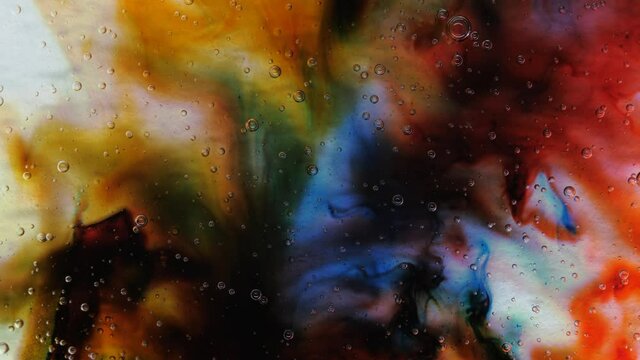 Transparent space liquid is filled with drops of red, blue, yellow and green paint.