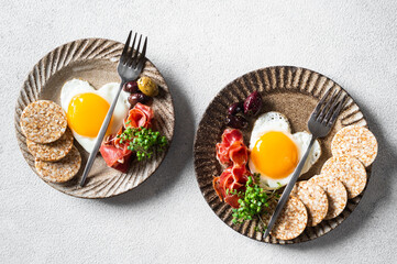 Romantic Breakfast on Women's Day - fried eggs in the shape of a heart and olives. Healthy breakfast. Rice cakes with eggs and hamon. Romantic breakfast. Top view.