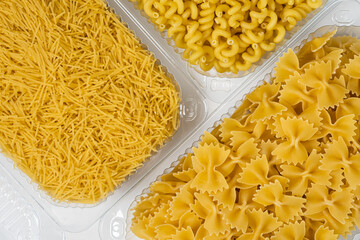 Close up of several types of dry pasta in a plate on white background