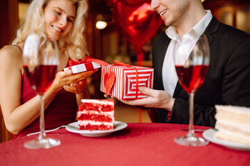Valentine's Day concept. Exchange of gifts. Beautiful young couple celebrating Valentine's Day  in the restaurant. Hug, kiss and enjoy spending time together.