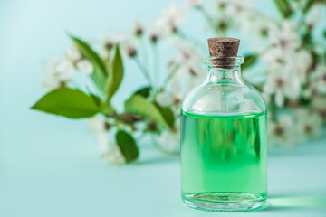 Bottle with natural cosmetic oil and flowers on a blue background. Aromatherapy and spa wellness concept. Organic skin care product.