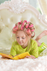 Lovely little girl with pink curlers reading