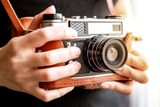 Woman holds old vintage film slr photo camera in leather cover in her hand