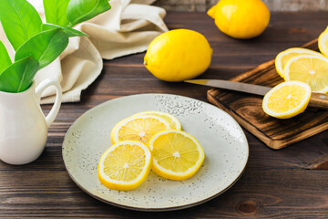 Round pieces of ripe lemons on a plate and on a wooden cutting board on the table. Organic nutrition, source of vitamins.