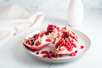 A whole ripe pomegranate divided into pieces on a plate on a light table. Organic natural food. Lifestyle