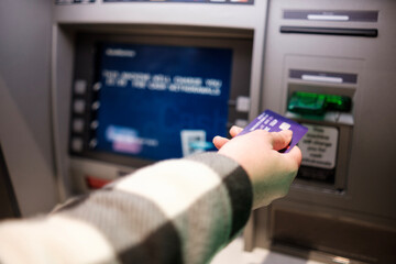 Female hand inserting credit card in cash machine.