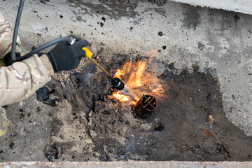 Downpipe repair. Heating the gutter area with a gas burner during repair of downpipe