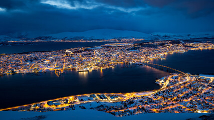 Fototapeta premium Panoramic view of Tromso, Norway, from Fjellheisen on mount Storsteinen at blue hour with pink illuminated clouds.