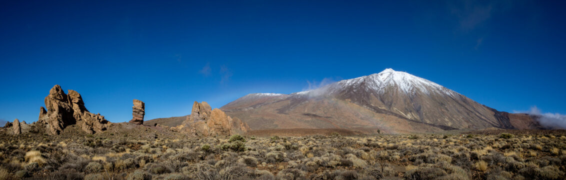 Panorama of caldera in Teide National Park, Tenerife, Canary Islands, Spain. Roques de Garcia in the foreground and snow covered mount Pico del Teide in the background.