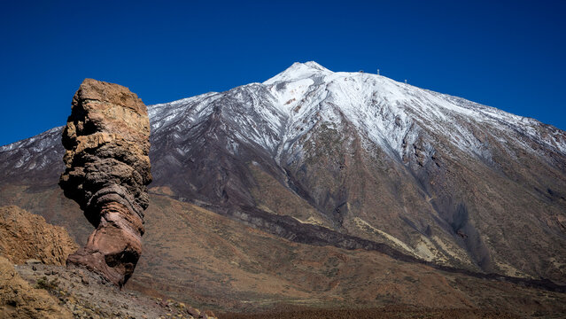 Rock formation Roque Cinchado "Finger of God", part of Roques de Garcia, in Teide National Park, Tenerife, Canary Islands, Spain. Snow covered Pico del Teide in the background.