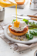 Pouring Hollandaise sauce over poached egg for cooking benedict egg for tasty breakfast. vertical...