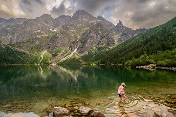 Tatra National Park, Poland. Wide angle of mountains lake Morskie Oko Or Eye of the Sea In autumn and a little girl walking in a lake. Beautiful Tatras Landscape.