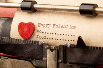 Happy Valentine - phrase on typewriter. Valentines Day greetings concept. Little red wooden heart...