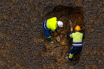 obreros cavadores profesionales con pico o pala o mineros cavando un agujero en la tierra