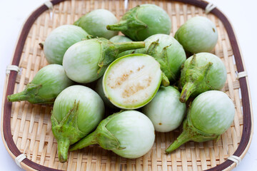 Organic green eggplant in bamboo basket on white background