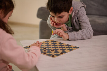 Concentrated school aged kids playing checkers at home