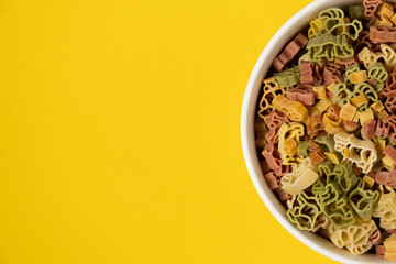 Pasta trottole tricolore wheat in a plate isolated on yellow background