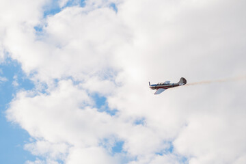 Small retro airplane, light aircraft flying in blue cloudy sky and doing stunts at Air Show....