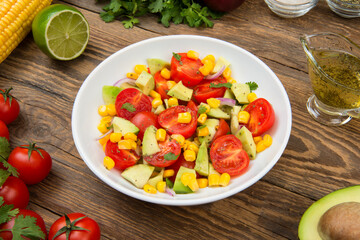 Avocado, tomato and corn salad with ingredients on an old rural table.  - 482254327