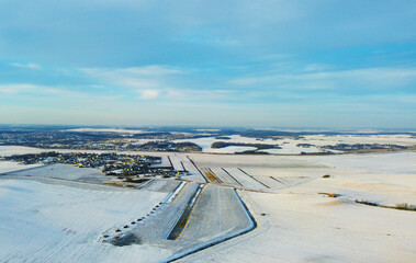 Top view photo of a winter suburban landscape with snowy fields, meadows and forests