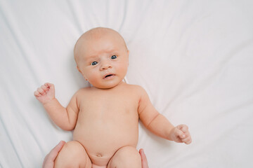 hands do exercises to baby on white sheet. exercise bike for a healthy tummy.