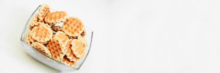 Belgian waffles in a glass bowl. holiday cookies on a white background. fresh baking concept. sweet desserts on a light texture