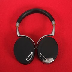 Black wireless headphones isolated on red background