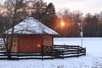Drewniany domek zasypany śniegiem o zachodzie słońca. Wooden house strewn with snow at sunset. © jarizPJ