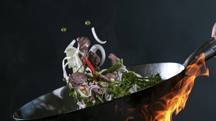 Freeze Motion of Wok Pan with Flying Ingredients in the Air and Fire Flames.