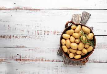 Raw small potatoes in a cast iron skillet on a beton background.
