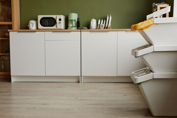 Side view background image of empty kitchen interior with focus on waste sorting containers in...