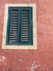 Fototapeta na wymiar Green shutter window in a faded ochre orange wall Rome Italy