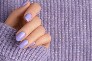 Beautiful womans hand in sweeter with purple fashionable spring nail design