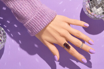 Beautiful womans hands in sweeter with purple fashionable spring nail design