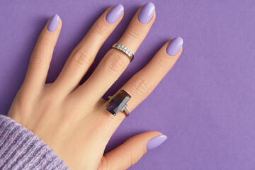 Beautiful womans hand in sweeter with purple fashionable spring nail design - obrazy, fototapety, plakaty