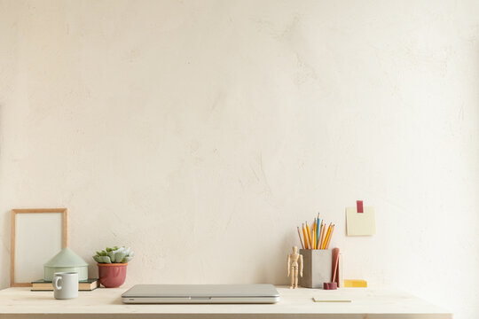 Home office, creative desk with office supplies and beige wall.