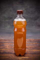 Plastic bottle of light beer lidded on brown wooden table on dark background