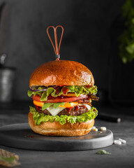 Delicious burger with cutlet, lettuce, tomatoes, onions and red sauce