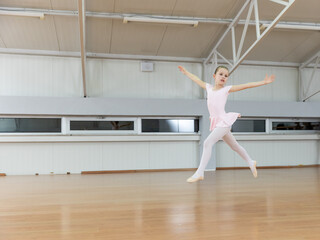 Fototapeta premium Young ballerina performing jump in ballet studio